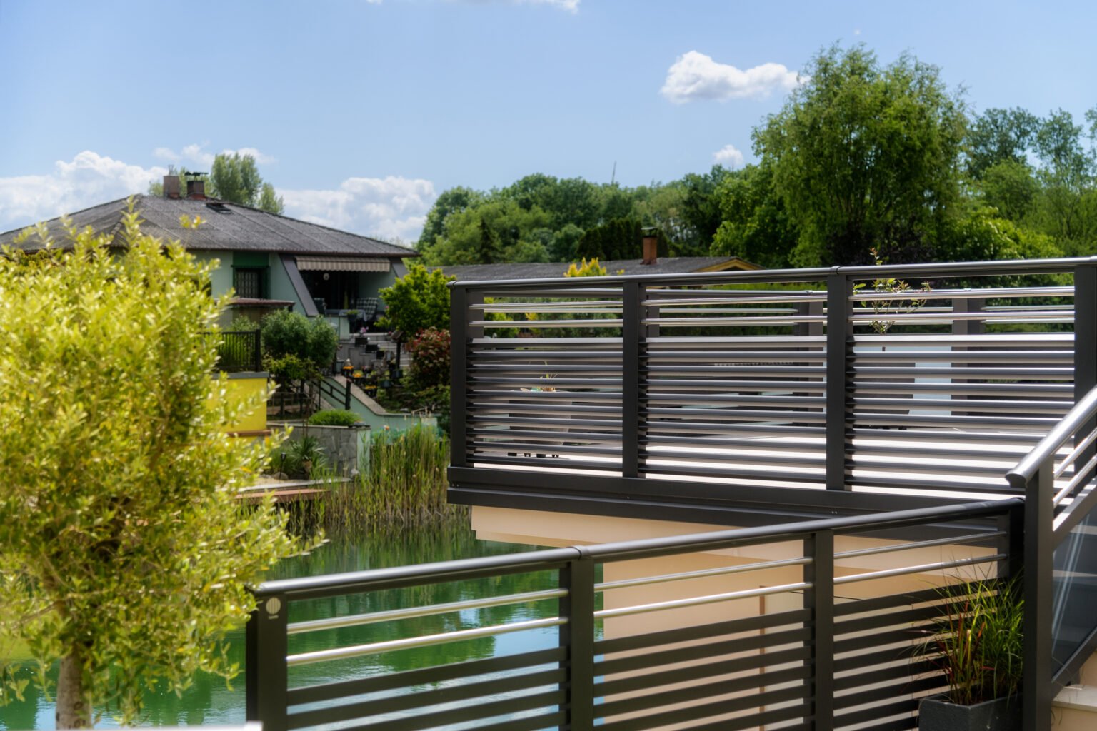 Alubalkon Barcelona mit Edelstahlstreben und Dreieckssprossen am See